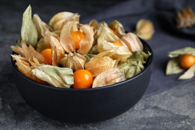 Ripe physalis fruits with dry husk on grey table, closeup