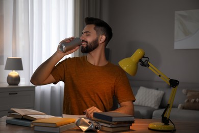 Young man with energy drink studying at home