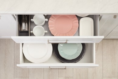 Clean plates, bowls and cutlery in drawers indoors, top view