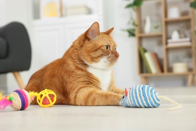 Photo of Cute ginger cat playing with toys at home