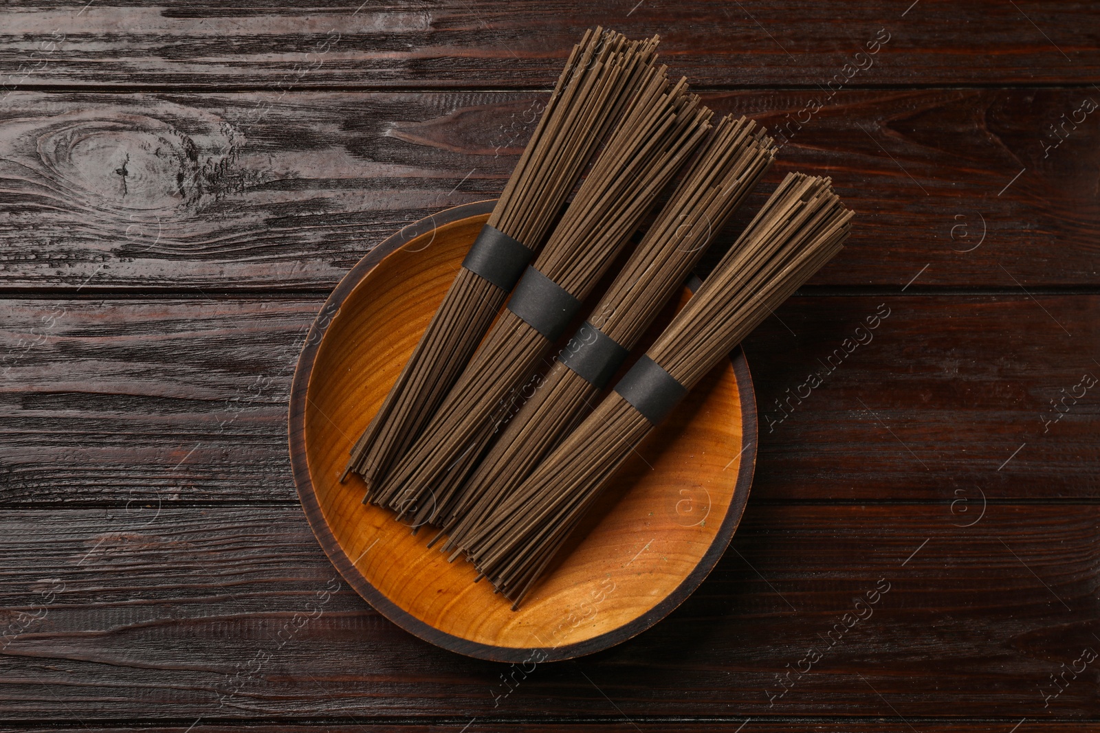 Photo of Uncooked buckwheat noodles (soba) on wooden table, top view