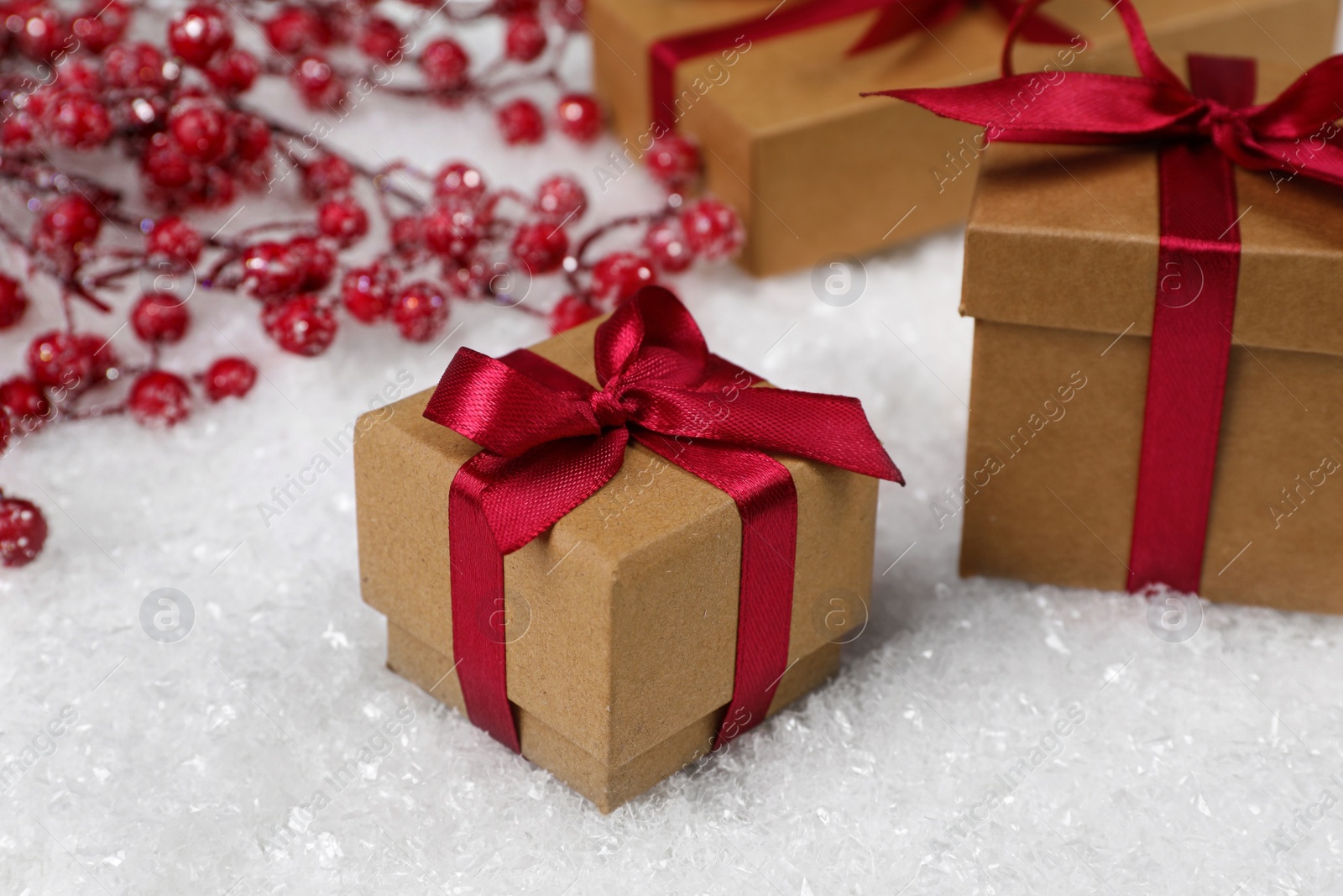 Photo of Gift boxes and decorative branches on artificial snow, closeup. Christmas celebration