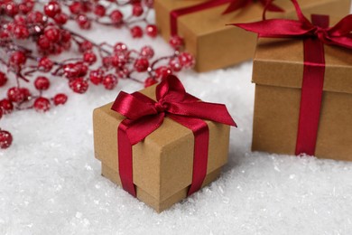 Photo of Gift boxes and decorative branches on artificial snow, closeup. Christmas celebration