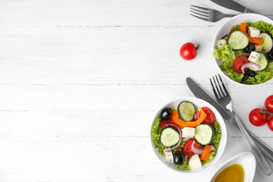 Photo of Tasty fresh Greek salad on white wooden table, flat lay. Space for text