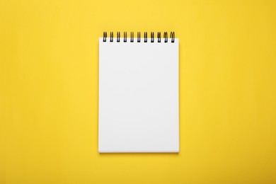 Photo of Blank office notebook on yellow background, top view