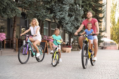 Photo of Happy family with children riding bicycles in city