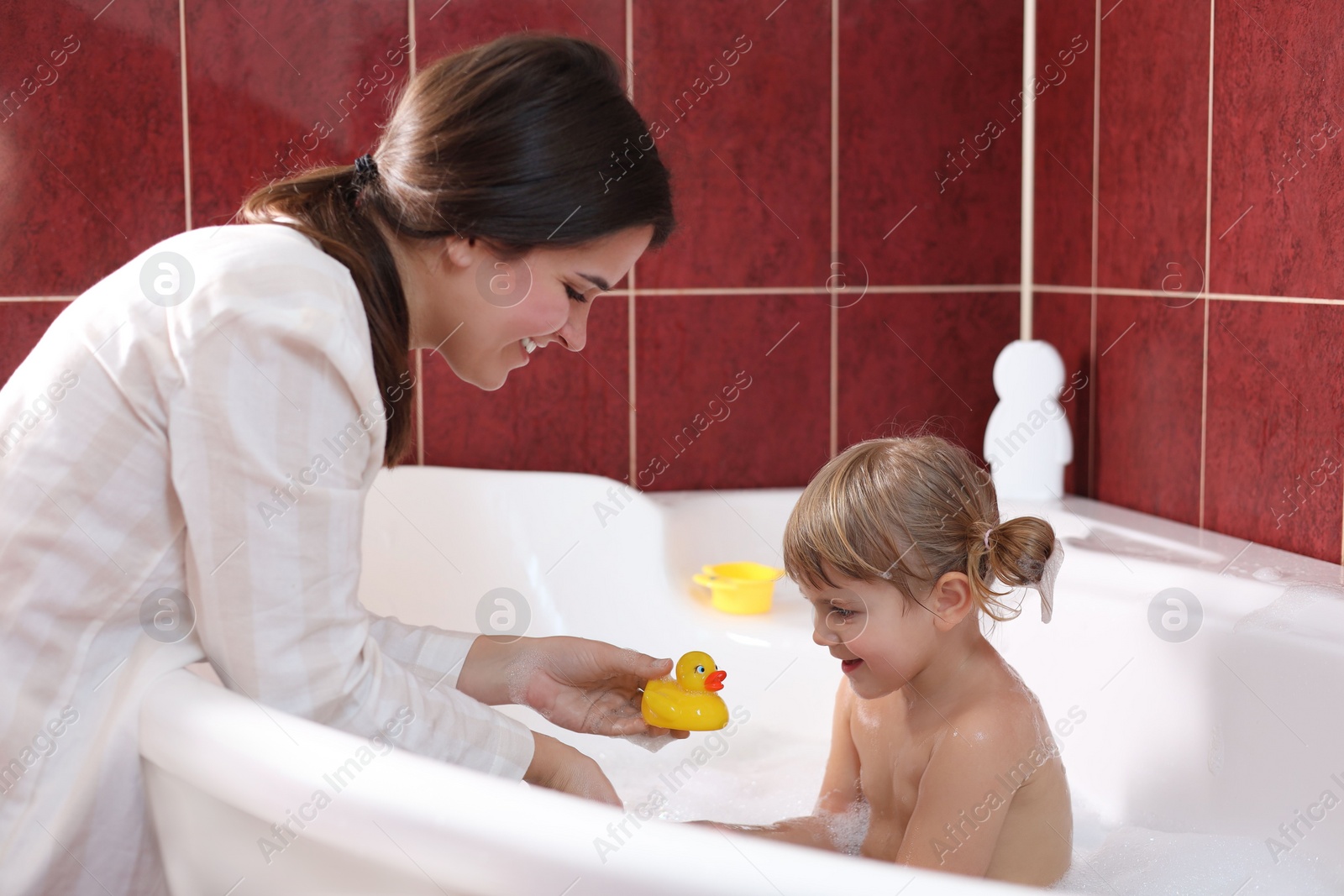 Photo of Happy mother playing with her little daughter in bathroom