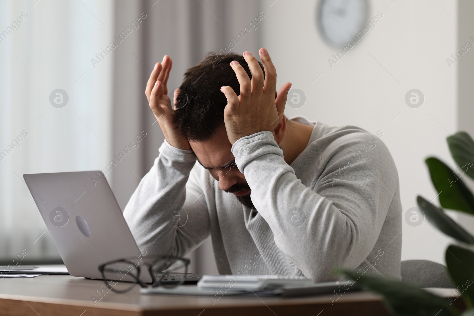 Photo of Man suffering from headache at workplace in office