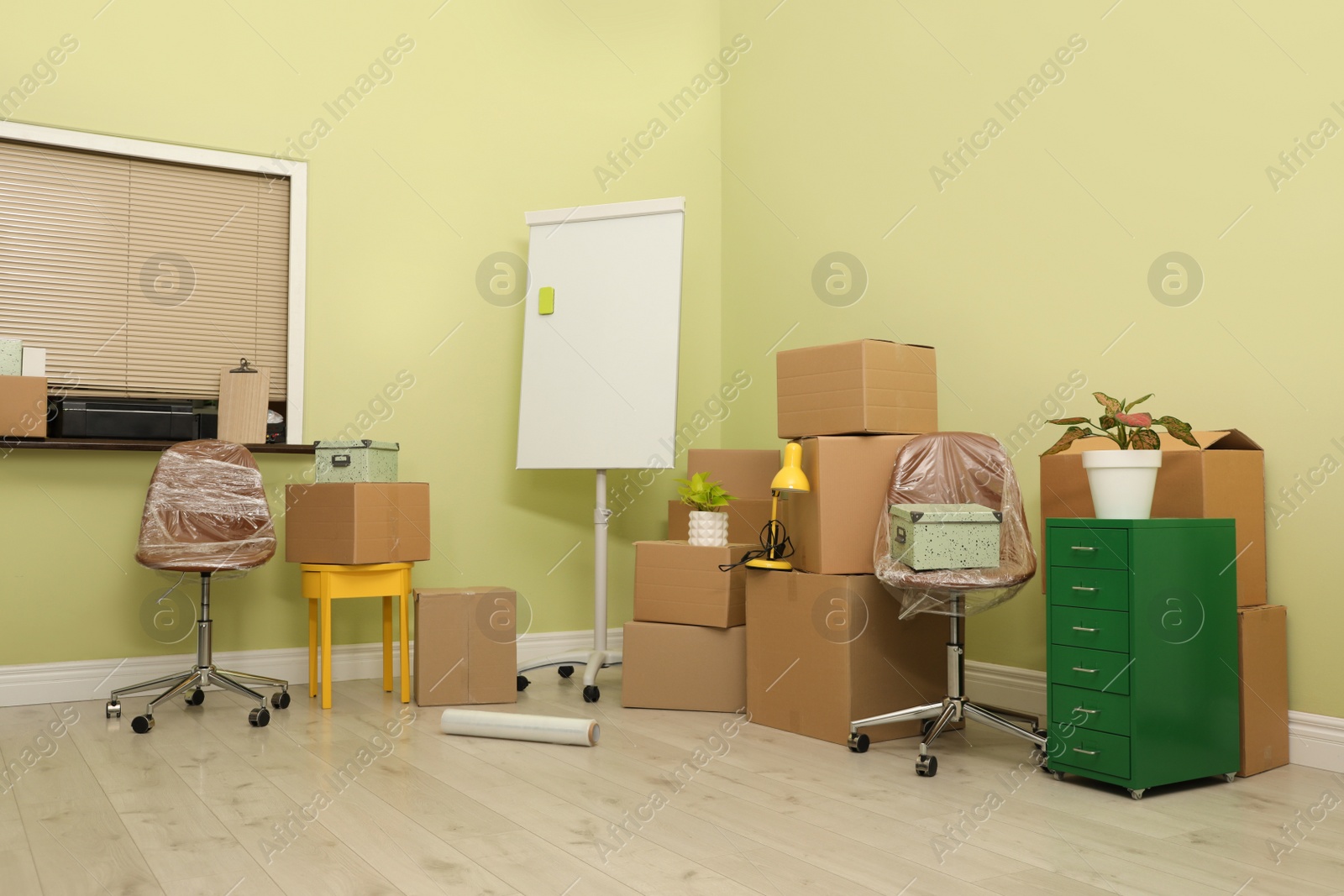 Photo of Cardboard boxes with packed stuff in new office. Moving day