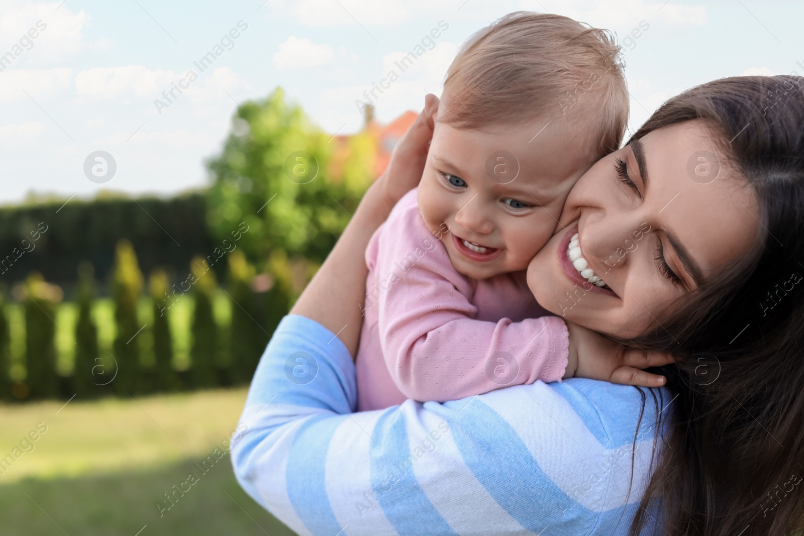 Photo of Happy mother with her cute baby at backyard on sunny day, space for text