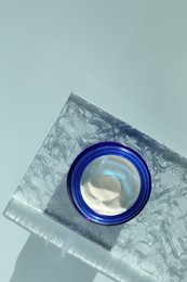 Jar of moisturizing cream on light blue background, top view