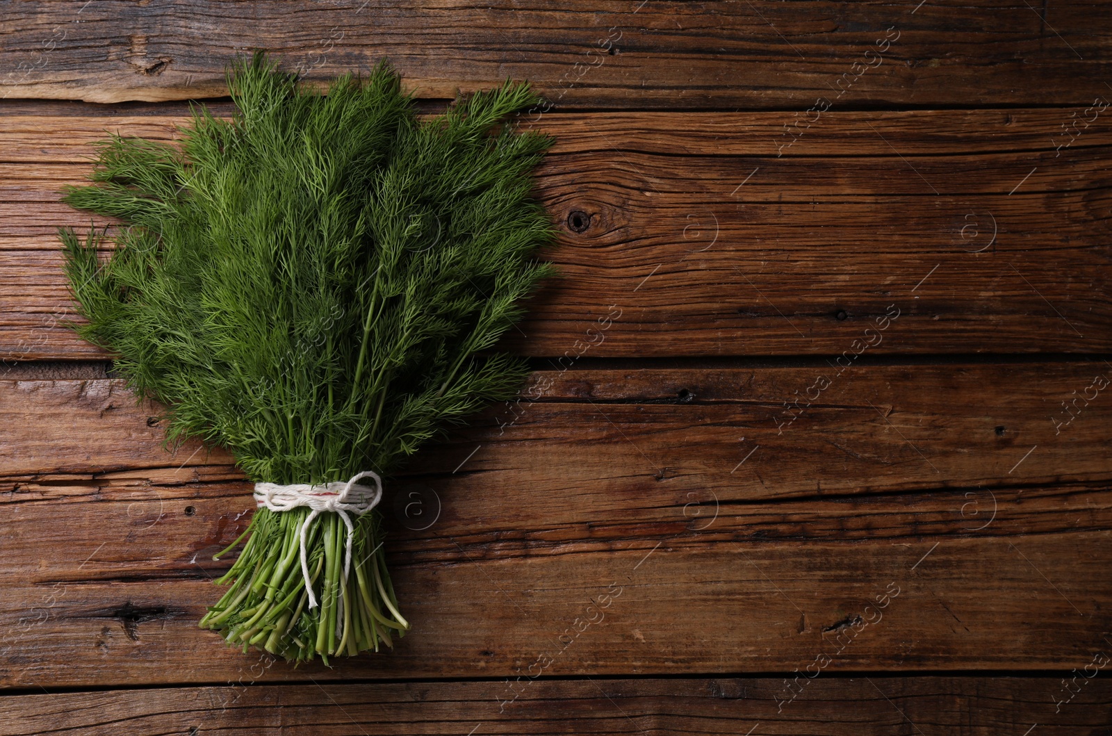 Photo of Bunch of fresh green dill on wooden table, top view. Space for text