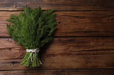 Photo of Bunch of fresh green dill on wooden table, top view. Space for text