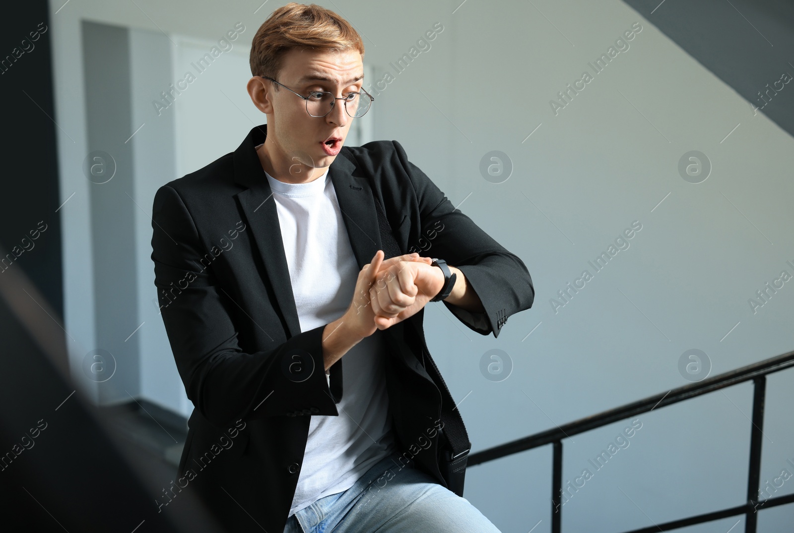 Photo of Emotional young man checking time in office. Being late