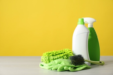 Photo of Bottles of cleaning products and supplies on light table. Space for text