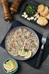 Photo of Tasty pickled anchovies served on grey textured table, flat lay