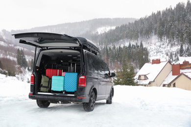 Black car with luggage in trunk on snowy road. Winter vacation