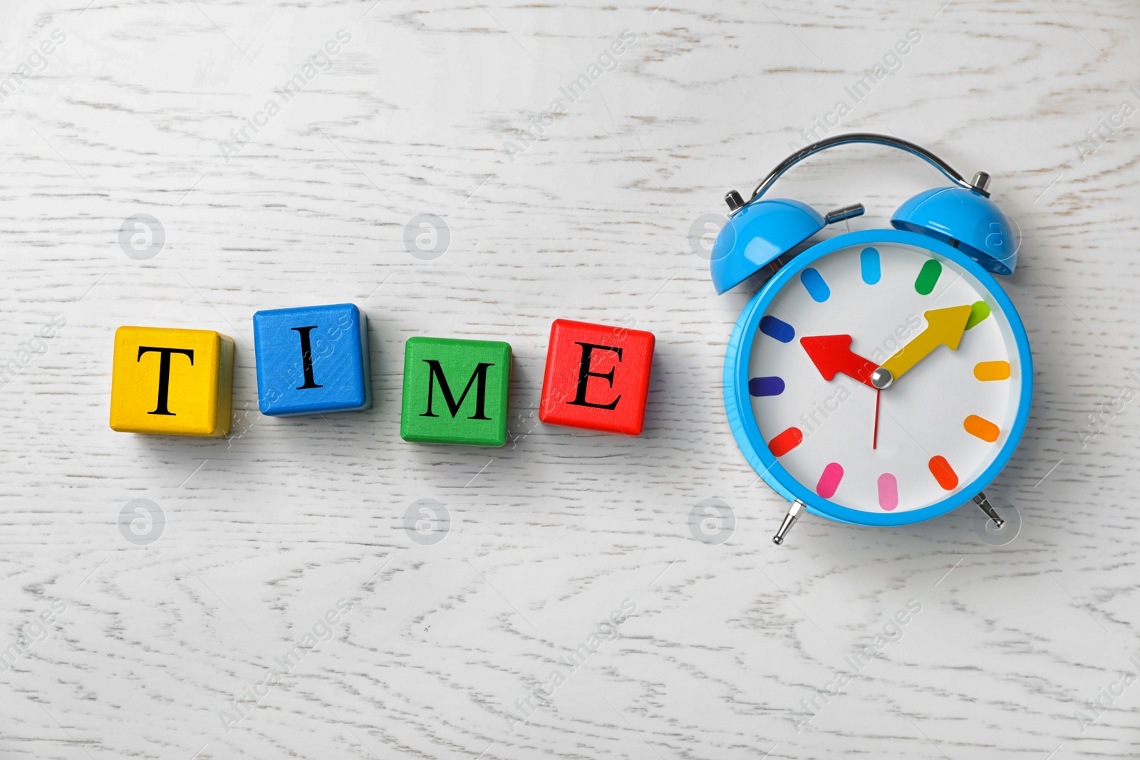 Photo of Flat lay composition with alarm clock and word TIME on colorful cubes against light background