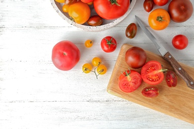 Photo of Flat lay composition with fresh ripe whole and cut tomatoes on white wooden table