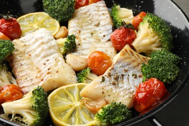 Tasty cod cooked with vegetables in frying pan, closeup