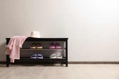 Photo of Storage bench with pairs of rubber slippers indoors. Space for text