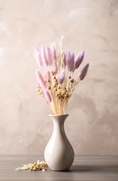 Photo of Dried flowers in vase on table against light grey background
