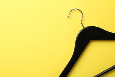 Photo of Black hanger on yellow background, top view. Space for text