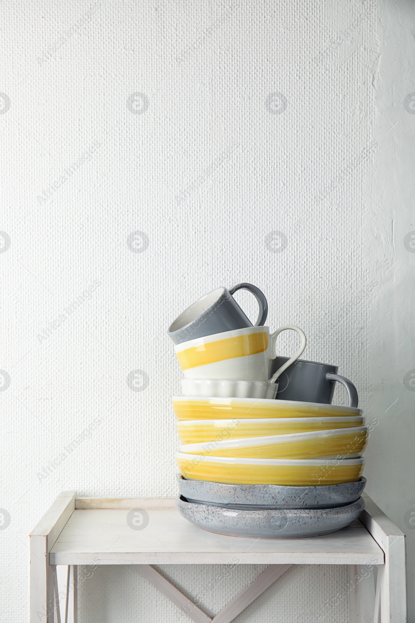 Photo of Set of dinnerware on table against light background with space for text. Interior element