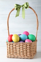 Colorful Easter eggs in wicker basket on white background