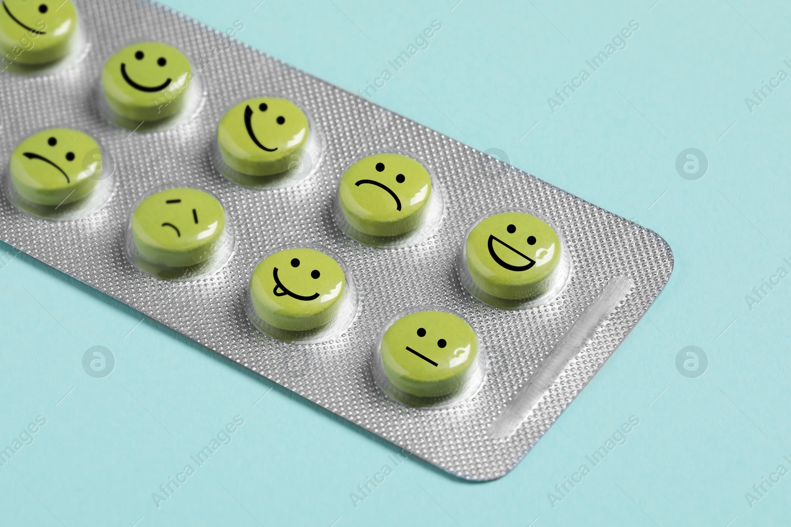 Image of Pills with different emotional faces in blister on light blue background