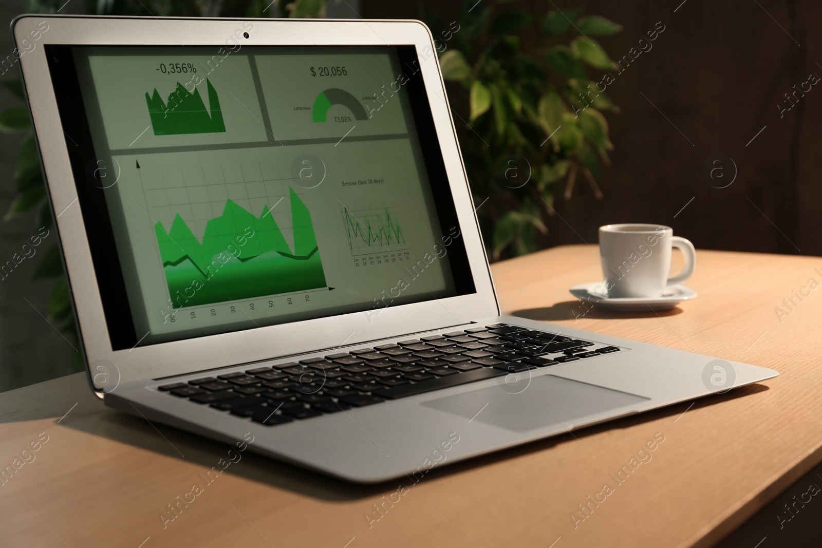 Photo of Modern laptop and cup of coffee on desk in office