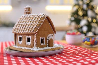 Photo of Beautiful gingerbread house decorated with icing on table indoors, space for text