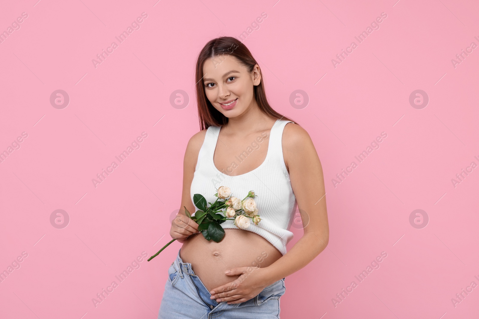 Photo of Beautiful pregnant woman with roses on pink background