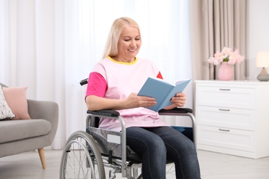 Mature woman in wheelchair with book at home
