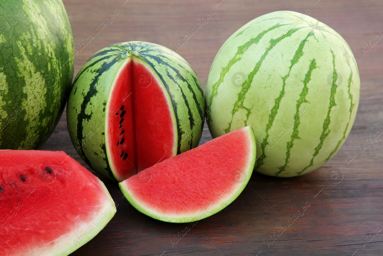 Photo of Different delicious ripe watermelons on wooden table