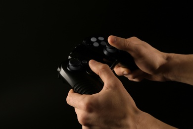 Man holding video game controller on black background, closeup