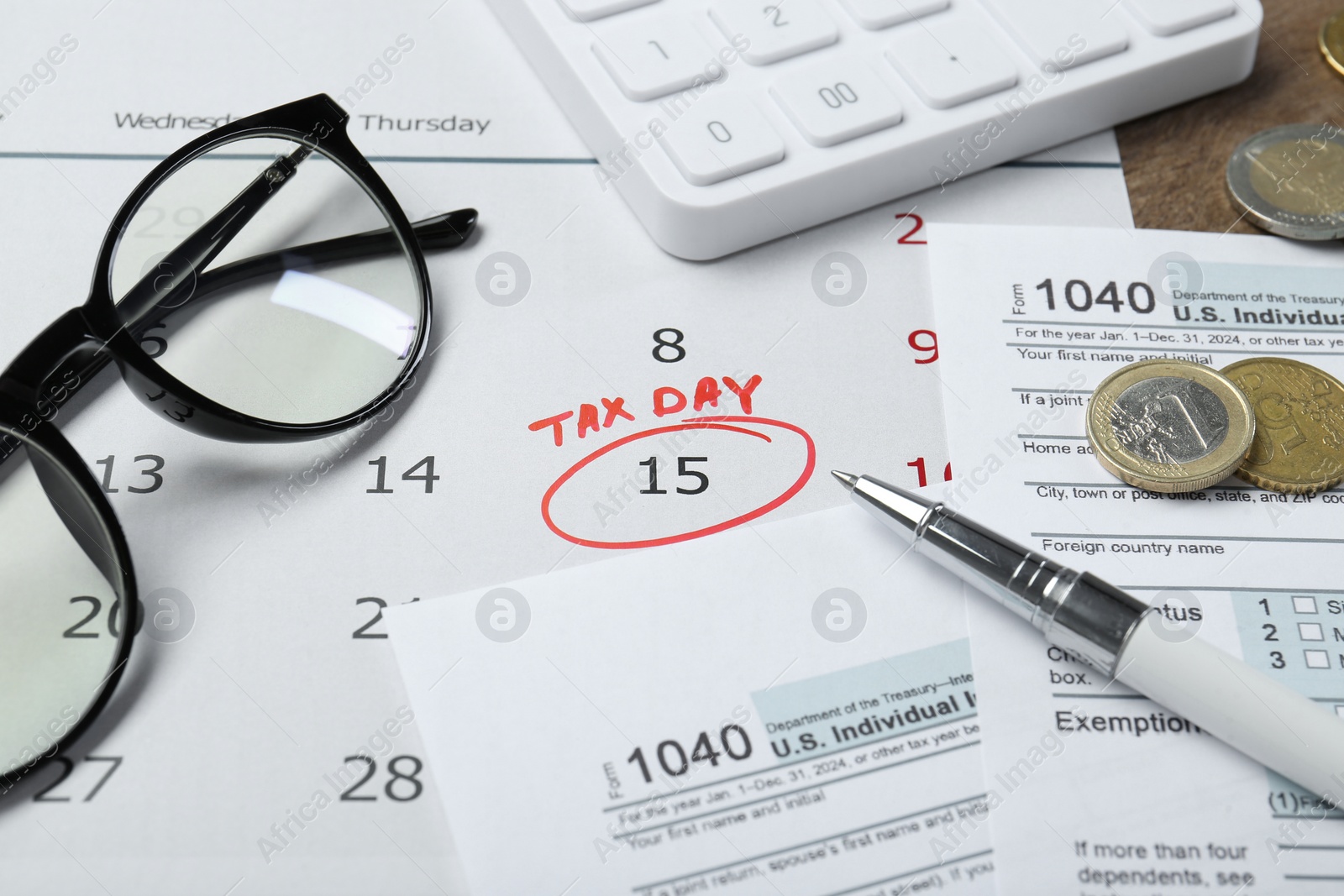 Photo of Calendar with date reminder about tax day, documents, pen, coins, glasses and calculator on table, closeup