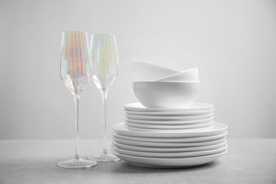 Set of clean dishes and glasses on light grey table