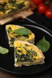 Photo of Pieces of delicious pie with spinach on wooden table, closeup