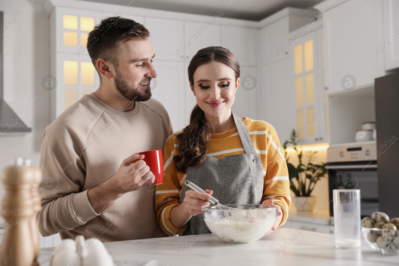 Photo of Lovely young couple cooking dough together in kitchen