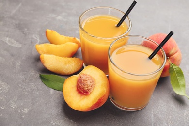 Photo of Natural peach juice and fresh fruits on grey table