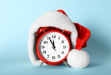 Photo of Alarm clock with Christmas decor on light blue background. New Year countdown