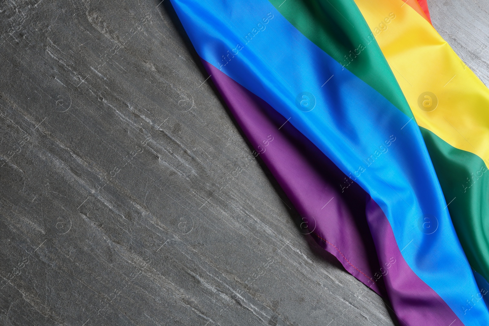 Photo of Bright rainbow gay flag on table, top view with space for text. LGBT community
