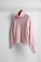 Photo of Warm sweater hanging on rack against white background