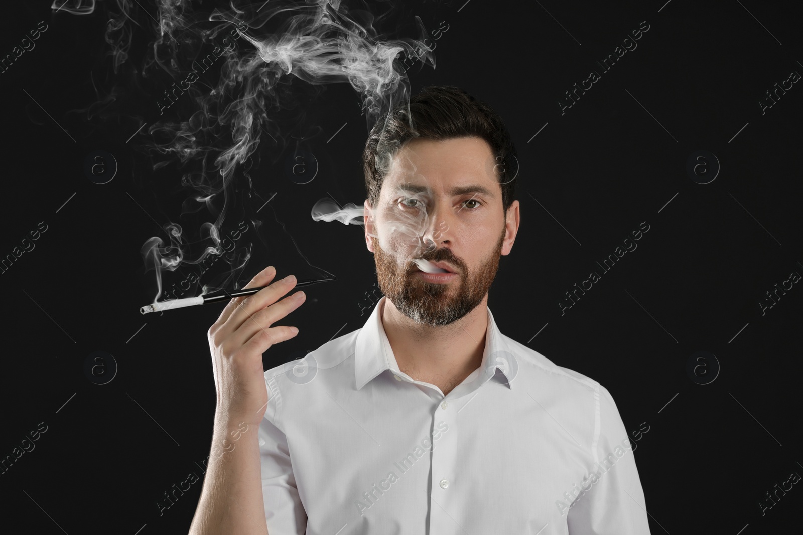 Photo of Man using long cigarette holder for smoking on black background