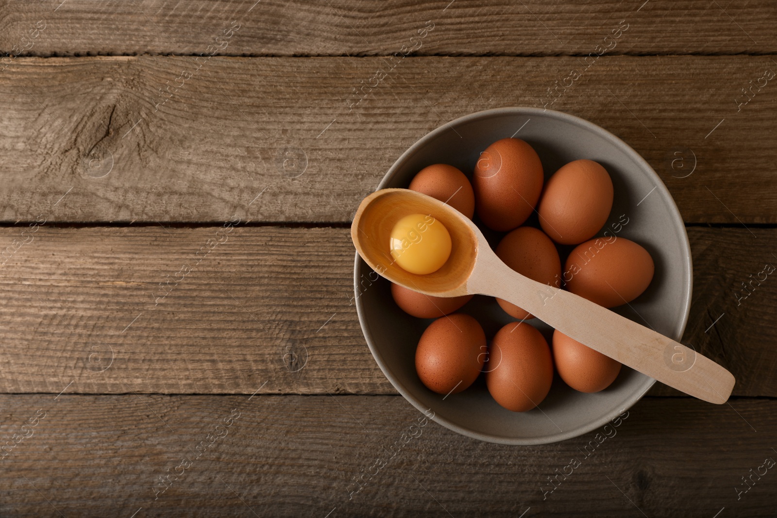 Photo of Raw chicken eggs on wooden table, top view. Space for text