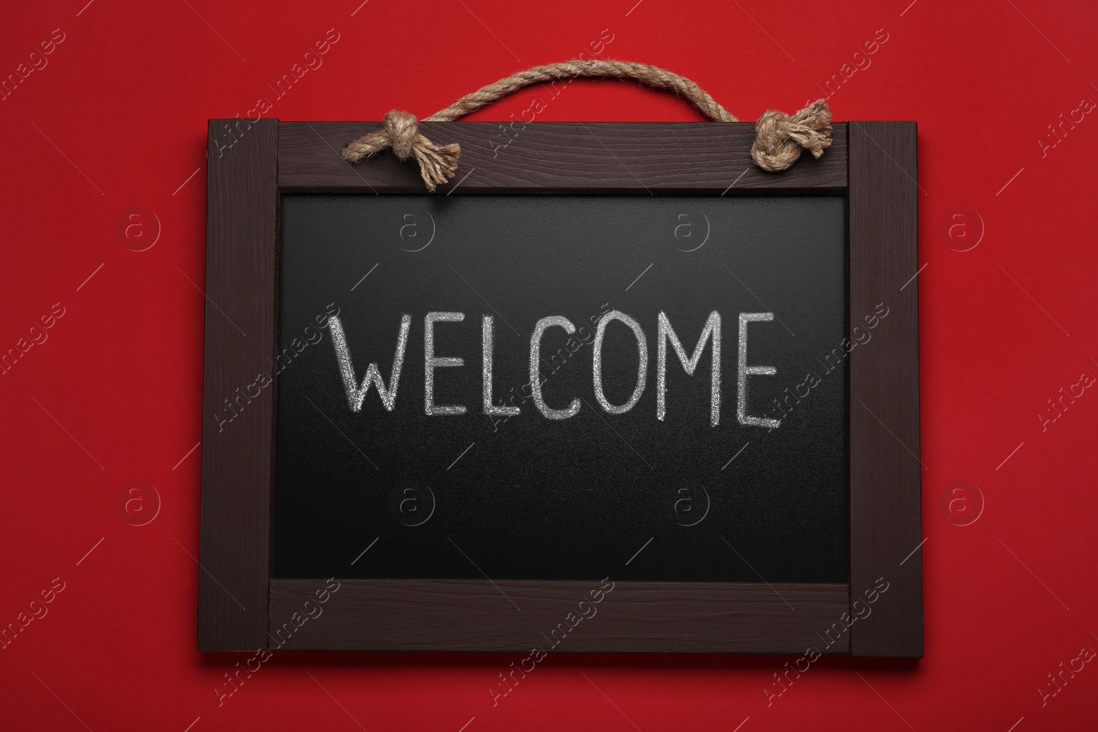 Photo of Small chalkboard with word Welcome on red background, top view