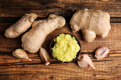 Photo of Fresh garlic and other natural cold remedies on wooden table, flat lay