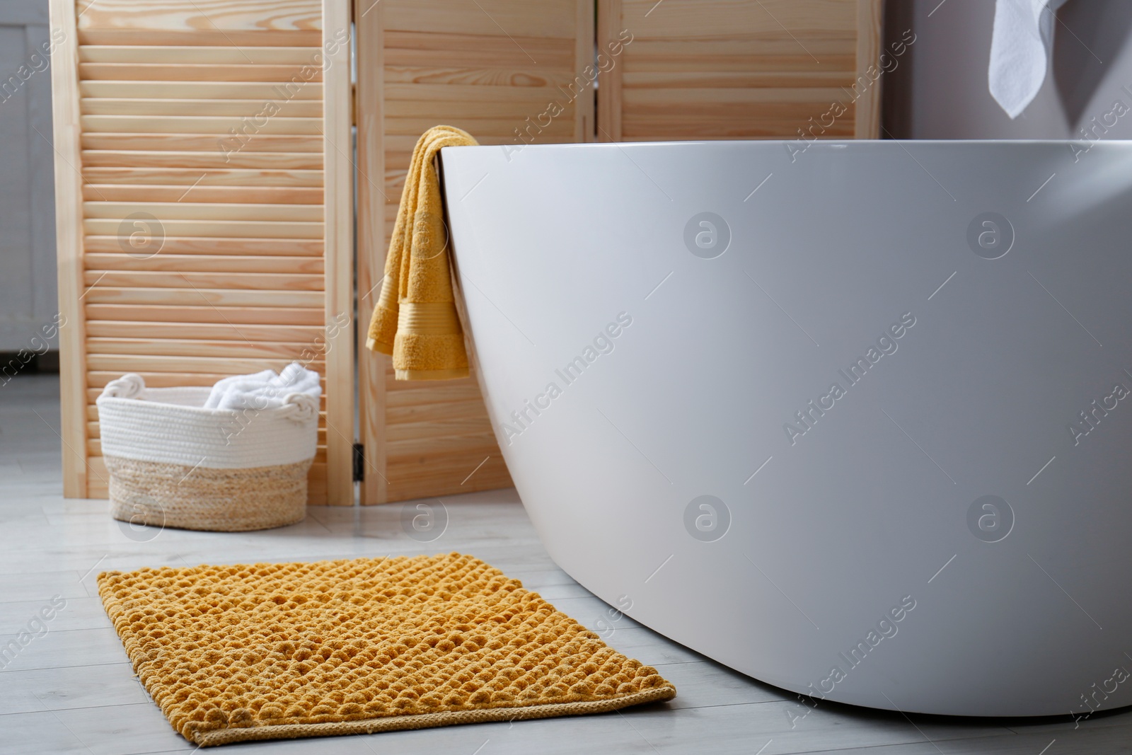 Photo of Soft orange mat on floor near tub in bathroom. Interior design