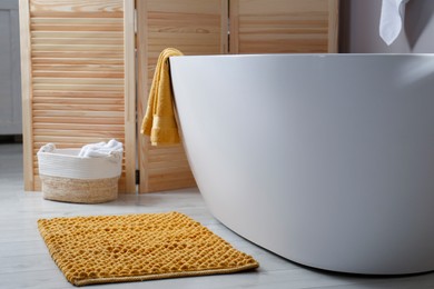 Soft orange mat on floor near tub in bathroom. Interior design